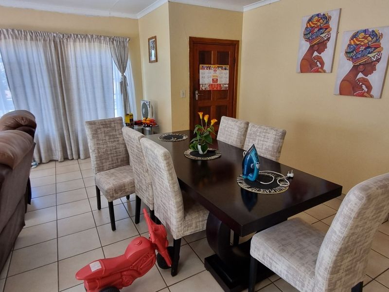 An open-plan living and dining area featuring neutral tiled flooring and a classic timber door, offering a functional and versatile space for daily living.