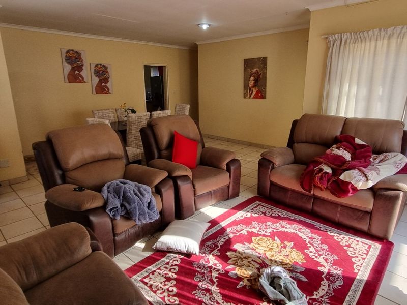 A spacious living area featuring neutral wall tones and tiled flooring, offering a comfortable and functional layout for family relaxation.