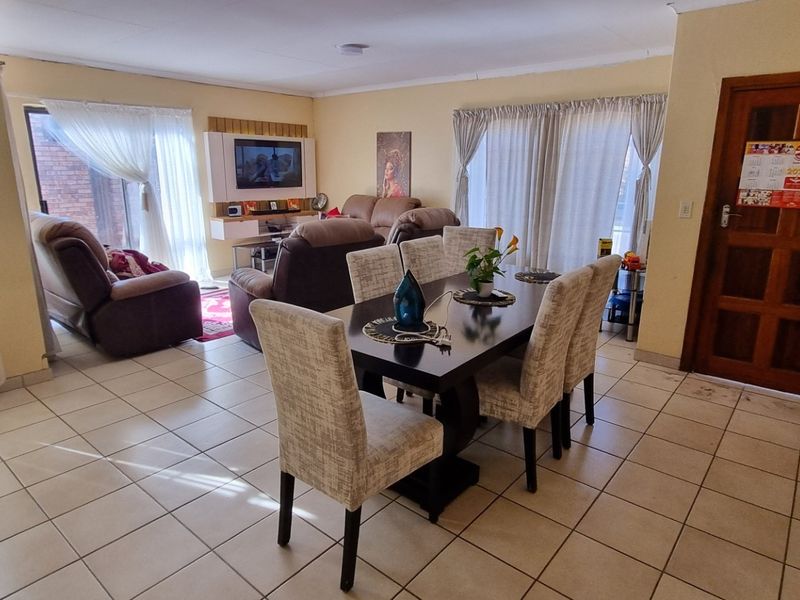 Open-plan living and dining area featuring tiled flooring, neutral walls, and sliding glass doors providing natural light.