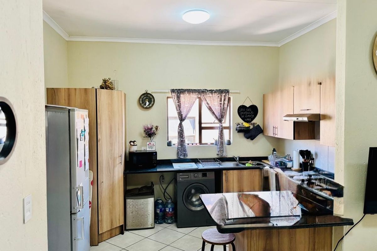 A functional kitchen featuring wood-look cabinetry, dark countertops, tiled flooring, and an integrated extractor fan, providing a practical workspace for daily cooking.