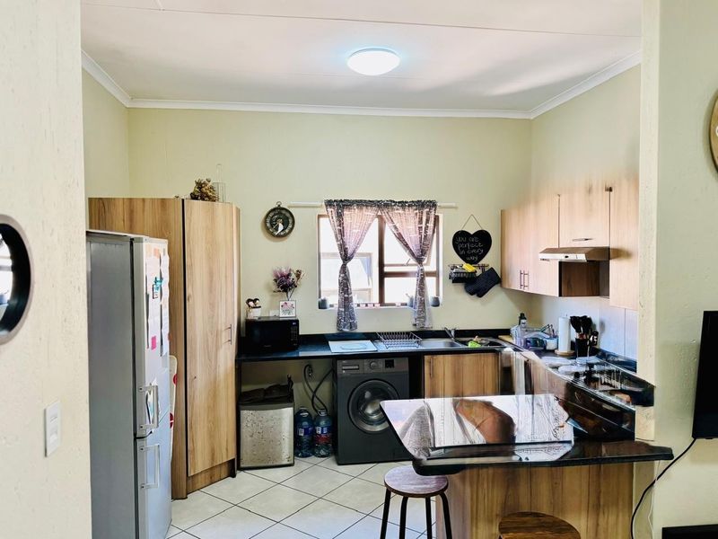 A functional kitchen featuring wood-look cabinetry, dark countertops, tiled flooring, and an integrated extractor fan, providing a practical workspace for daily cooking.