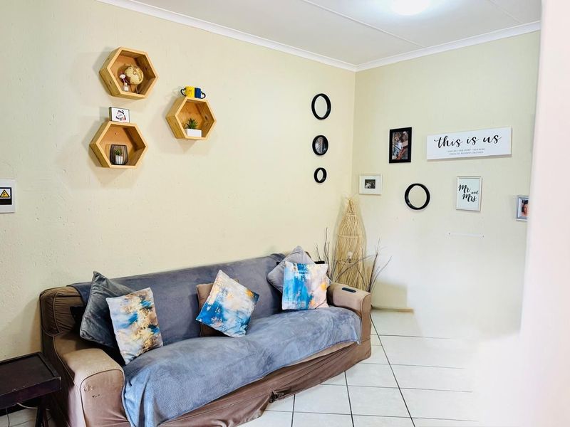 A living room area featuring neutral wall finishes, tiled flooring, and coved ceiling details, providing a functional space for relaxation.