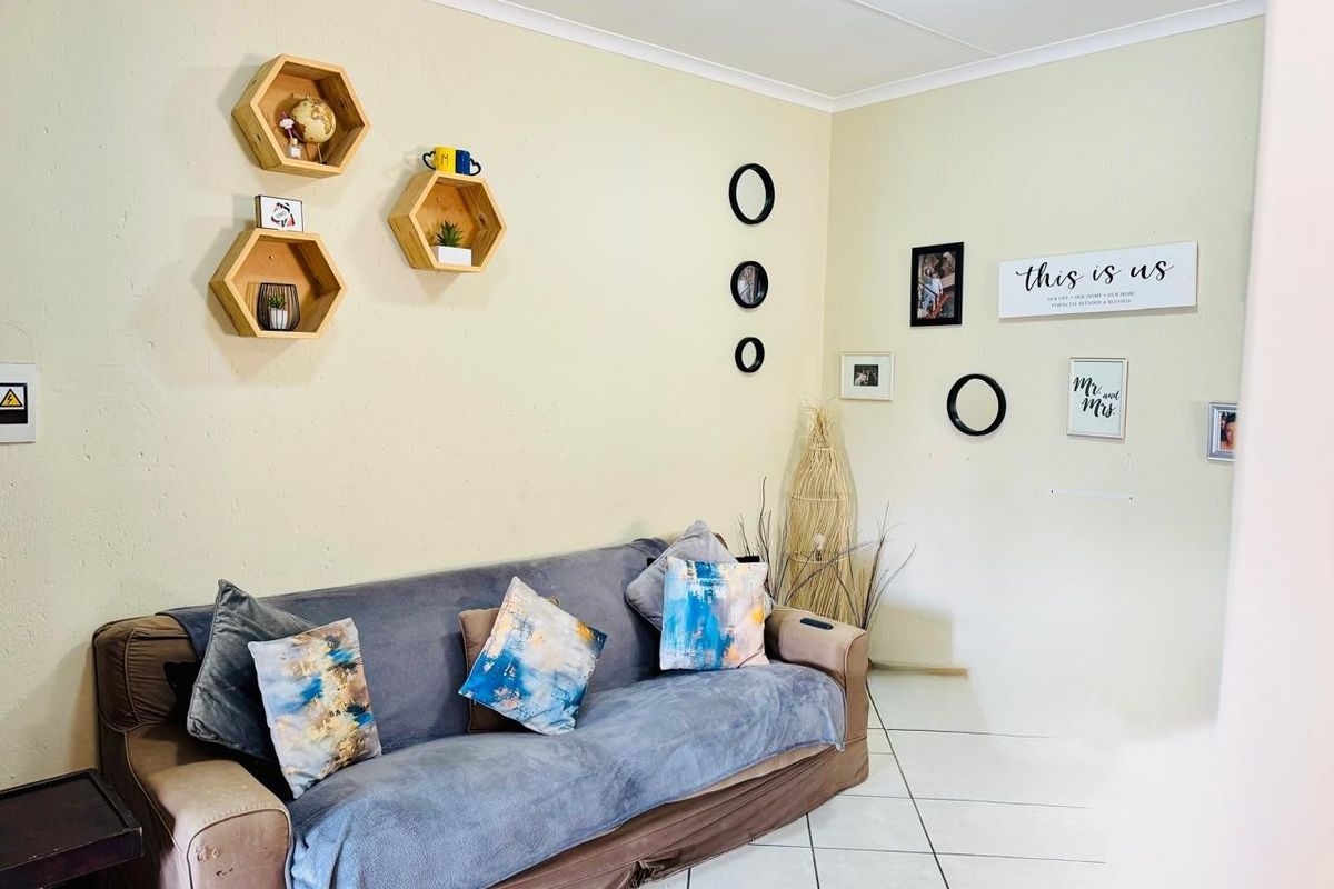 A living room area featuring neutral wall finishes, tiled flooring, and coved ceiling details, providing a functional space for relaxation.