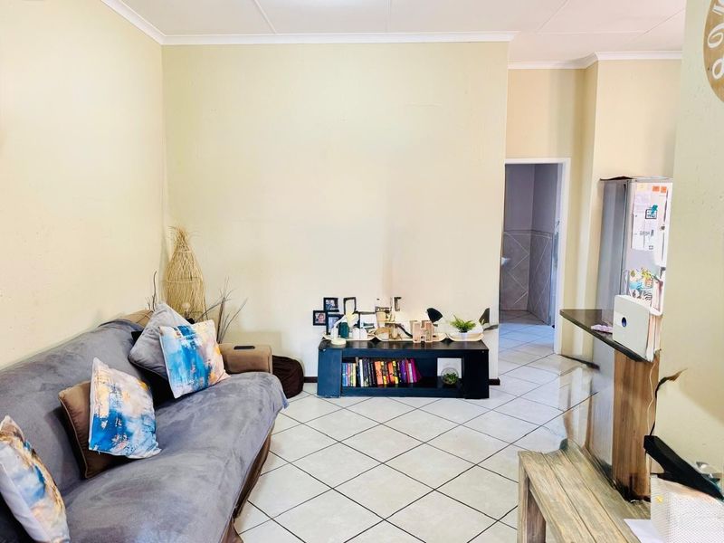 Open plan living area featuring neutral wall tones and ceramic floor tiles, providing a functional space with access to adjacent rooms.