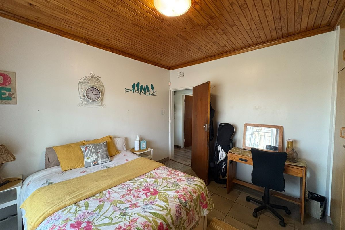 A bedroom featuring a timber tongue and groove ceiling, tiled flooring, and a built-in cupboard, offering a functional and lived-in space.