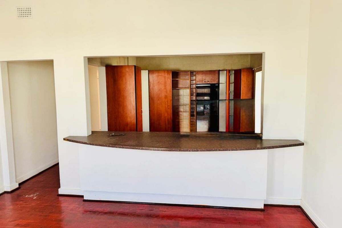 An empty kitchen area featuring a breakfast bar, built-in cabinetry, and hardwood flooring, offering a blank canvas for potential renovation and modernization.