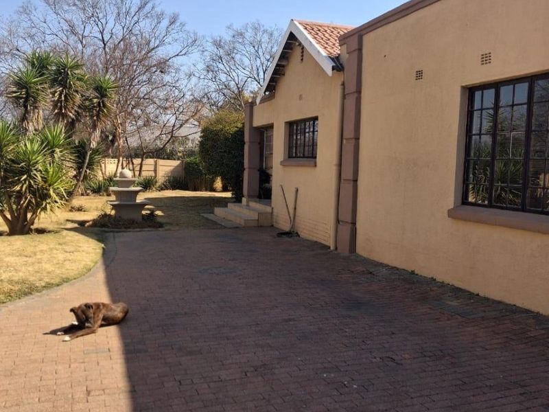 Rear exterior view of the cottage featuring a brick paved driveway, stone fountain, and established garden area.