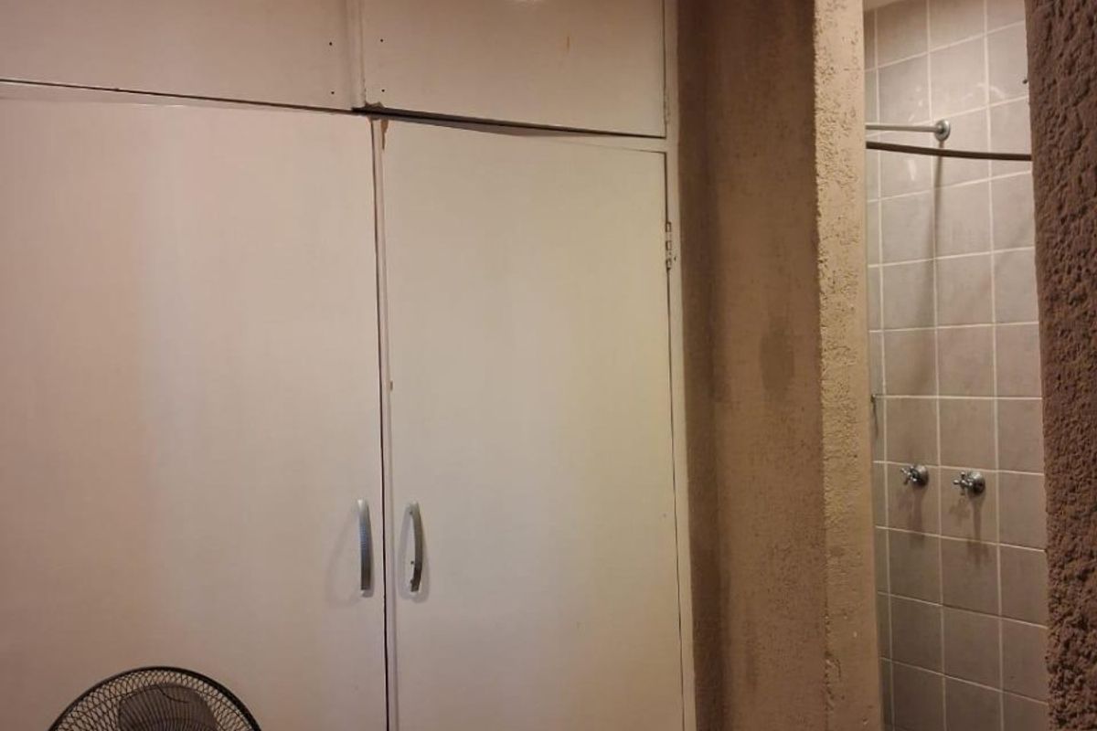 Bathroom area featuring built-in storage cupboards and a tiled shower enclosure with exposed plumbing fixtures.