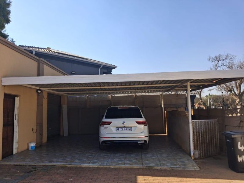 A covered carport area featuring tiled flooring and secure perimeter walling, providing sheltered off-street parking.