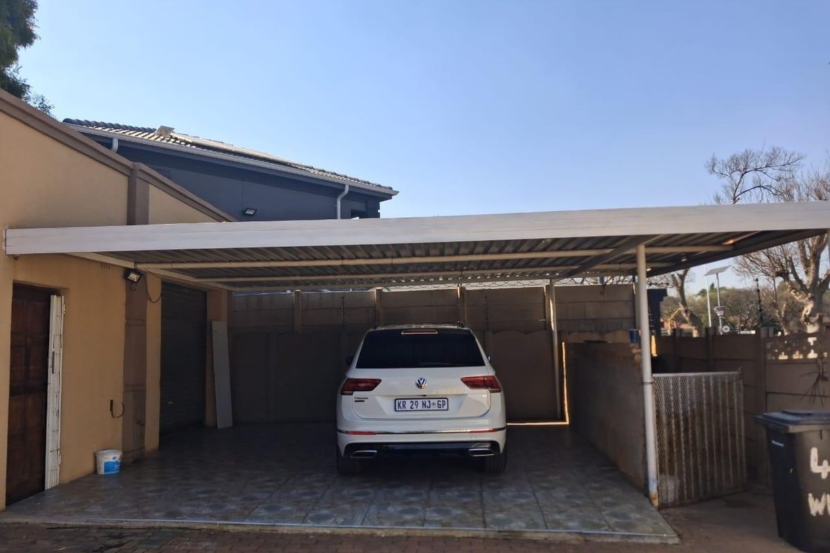 A covered carport area featuring tiled flooring and secure perimeter walling, providing sheltered off-street parking.