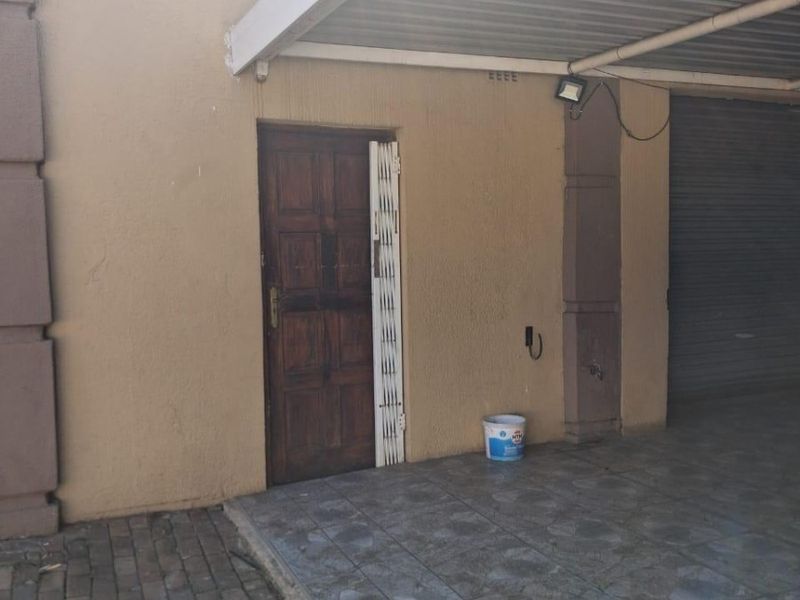 A covered garage area featuring tiled flooring, a security gate, and an external water tap.