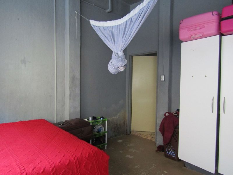 A bedroom featuring a built-in wardrobe, showing signs of damp on the lower walls and requiring cosmetic attention to finishes.