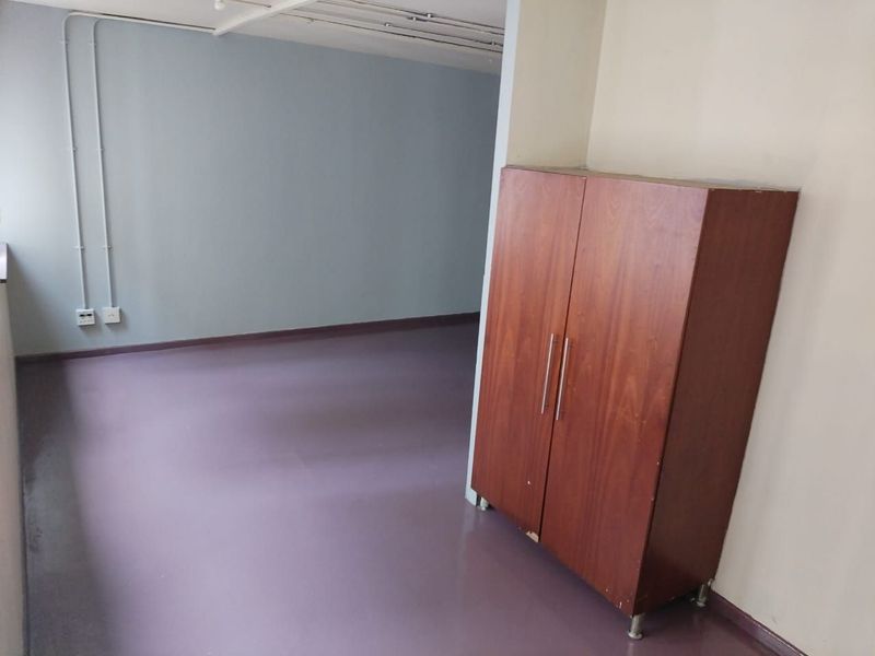 An empty bedroom featuring vinyl flooring and exposed electrical conduit, offering a blank canvas for renovation or interior design updates.