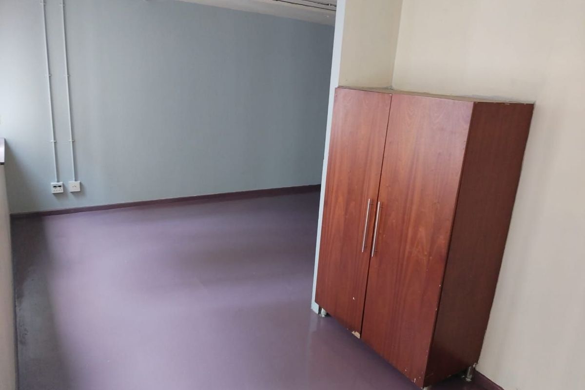 An empty bedroom featuring vinyl flooring and exposed electrical conduit, offering a blank canvas for renovation or interior design updates.