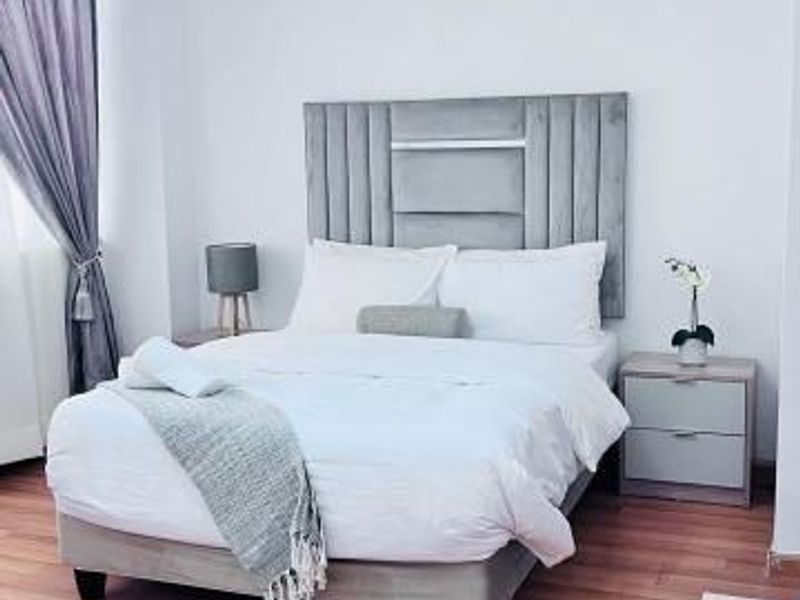 A bedroom featuring laminate flooring and a suspended ceiling with track lighting.