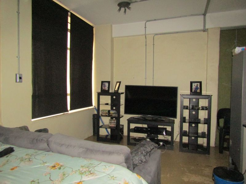 A living room area featuring exposed electrical conduit and roller blinds, requiring cosmetic updates to improve the overall aesthetic and finish.