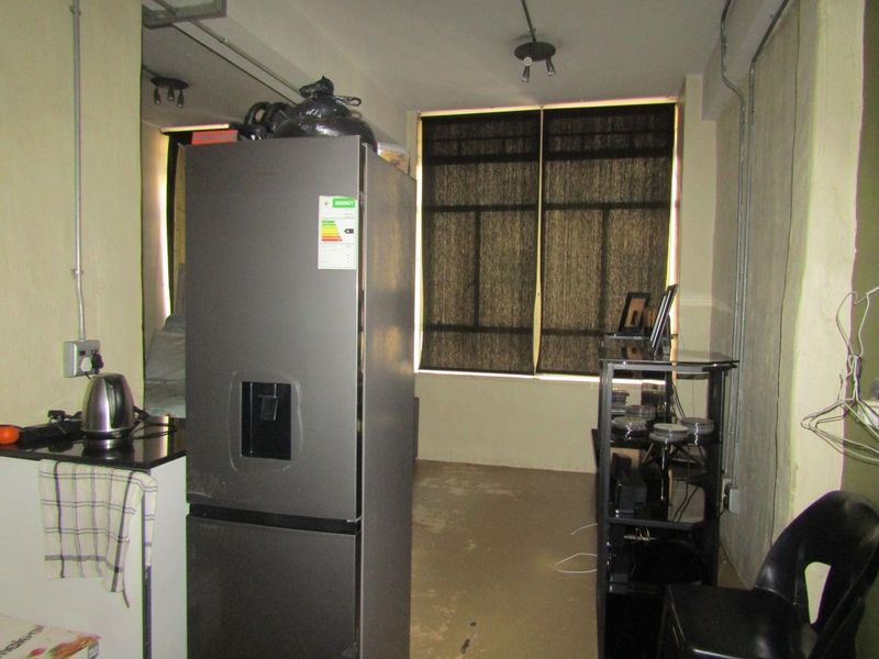 A compact kitchen area featuring granite countertops and exposed industrial-style electrical conduit, requiring cosmetic updates to improve the overall finish and aesthetic.