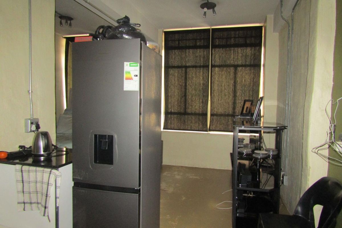 A compact kitchen area featuring granite countertops and exposed industrial-style electrical conduit, requiring cosmetic updates to improve the overall finish and aesthetic.