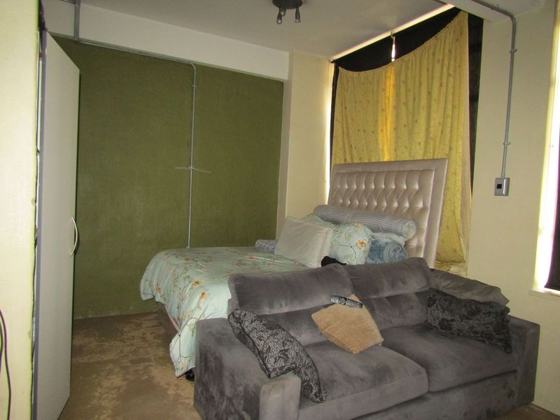 A bedroom featuring exposed electrical conduit and a built-in wardrobe, requiring cosmetic updates to improve the overall finish and aesthetic appeal.