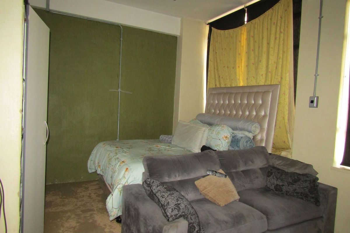 A bedroom featuring exposed electrical conduit and a built-in wardrobe, requiring cosmetic updates to improve the overall finish and aesthetic appeal.