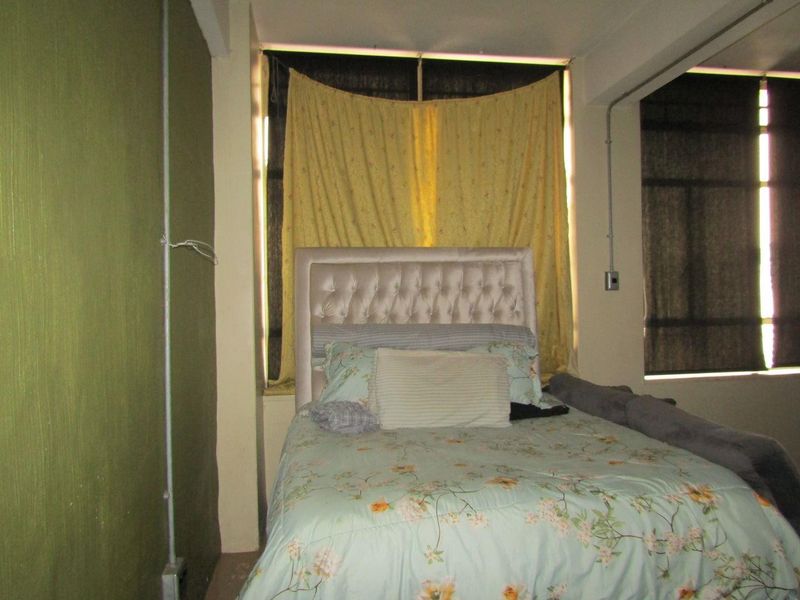 A bedroom featuring exposed electrical conduit and dated wall finishes, requiring cosmetic updates to improve the overall aesthetic and modern appeal.