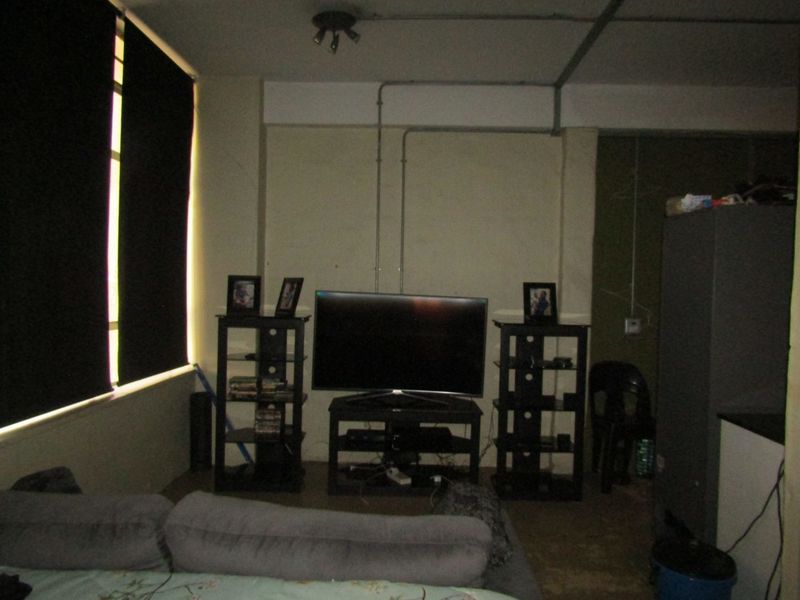 A living area featuring exposed electrical conduit and large windows, requiring cosmetic updates to improve the overall aesthetic and finish.