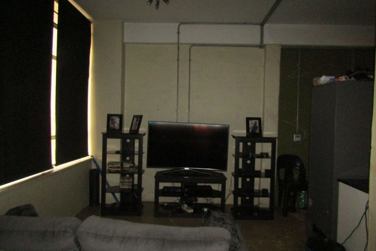 A living area featuring exposed electrical conduit and large windows, requiring cosmetic updates to improve the overall aesthetic and finish.