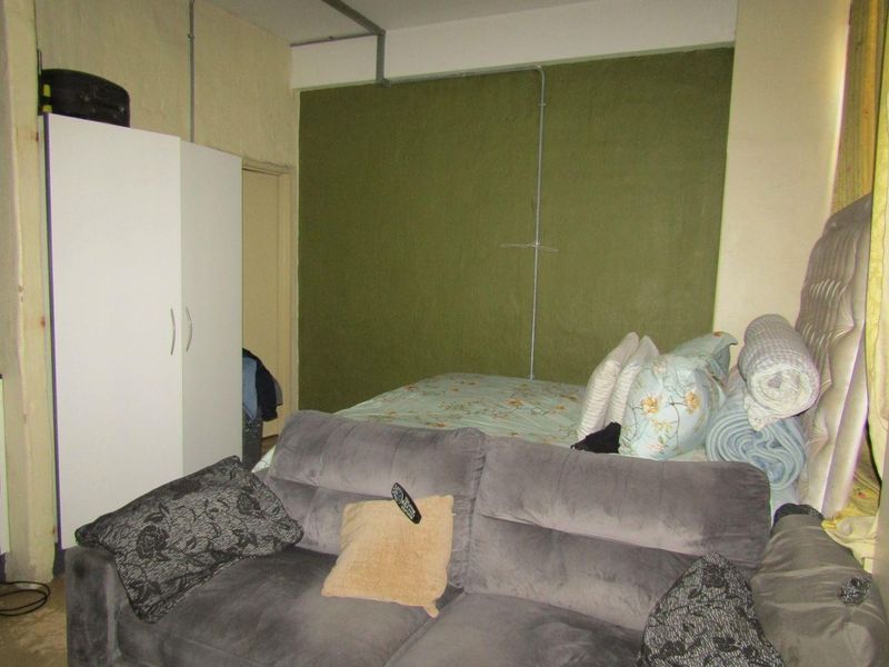 A bedroom space featuring exposed electrical conduit and painted wall finishes, requiring cosmetic updates to improve the overall aesthetic and finish quality.