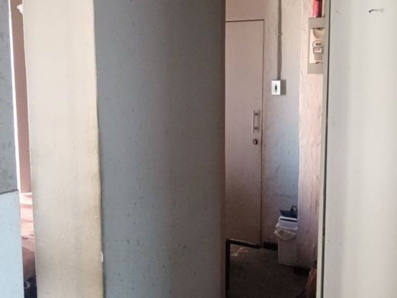A narrow interior hallway showing signs of wear, featuring exposed electrical conduit and plain wall finishes.