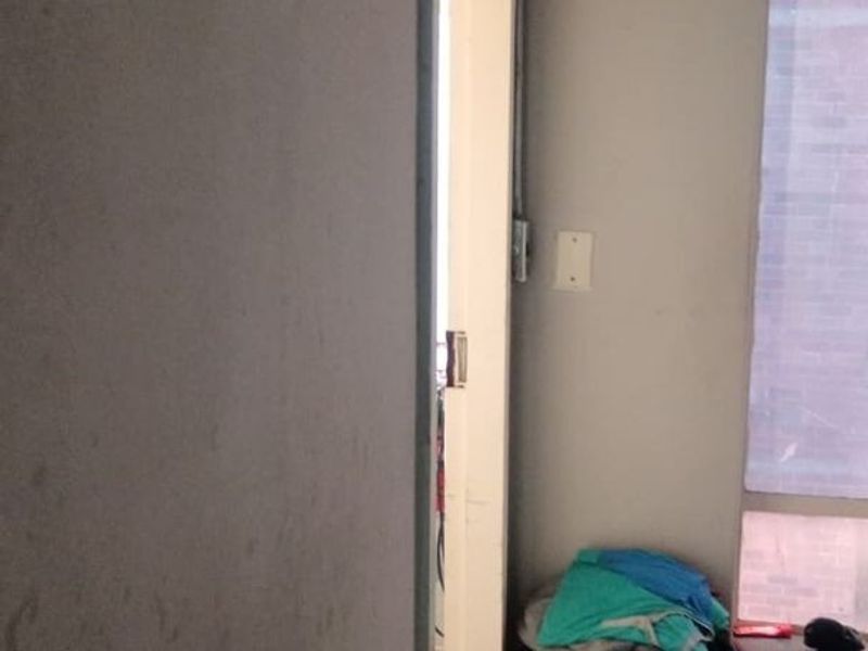 A narrow hallway area featuring exposed electrical conduit and stained wall finishes, requiring maintenance and cosmetic updates.