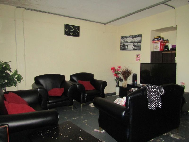 A living room space featuring exposed electrical conduit and worn flooring, requiring cosmetic updates to improve the overall condition and aesthetic appeal.
