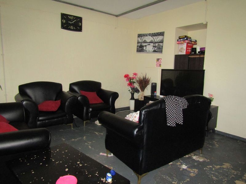 A living room area featuring a built-in wall niche, currently showing significant wear to the flooring and wall finishes.