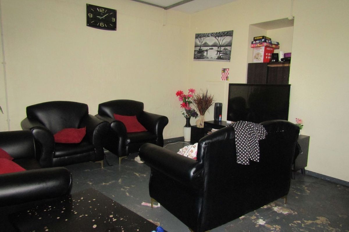 A living room area featuring a built-in wall niche, currently showing significant wear to the flooring and wall finishes.