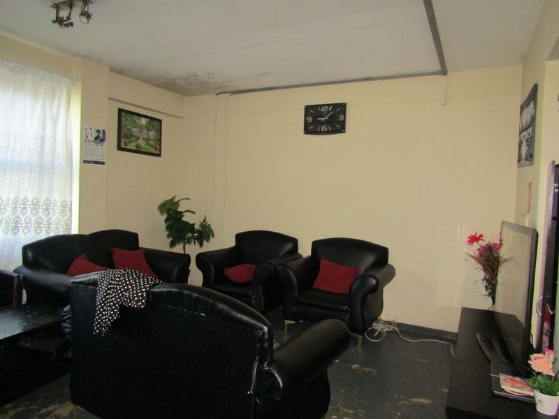 A living room area featuring visible ceiling water damage and exposed surface-mounted electrical conduit along the ceiling.