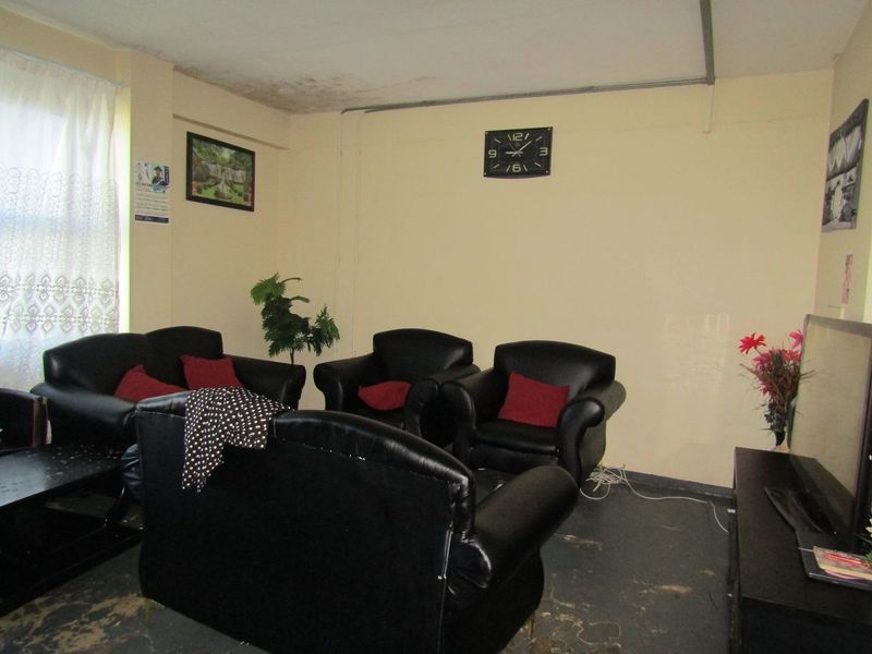 A living room area featuring visible ceiling water damage and worn flooring, requiring maintenance and cosmetic updates.