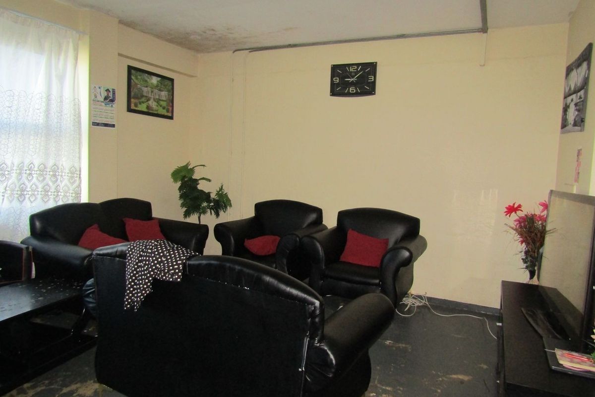 A living room area featuring visible ceiling water damage and worn flooring, requiring maintenance and cosmetic updates.