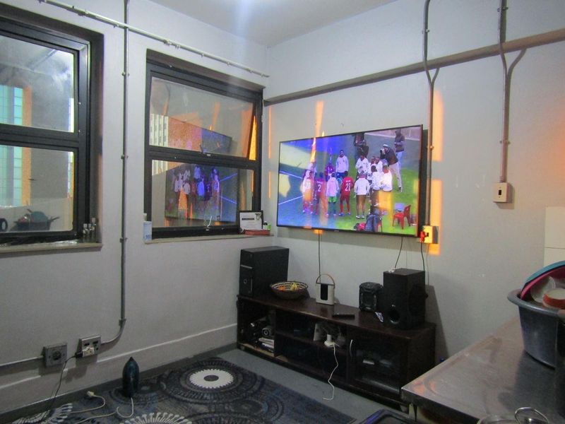 A living area featuring exposed electrical conduit and aluminium window frames, requiring cosmetic updates to improve the overall aesthetic and finish.