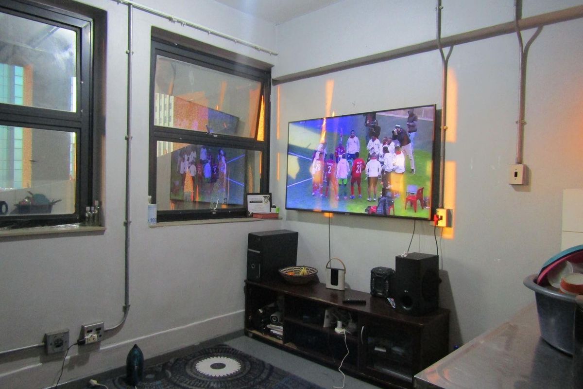 A living area featuring exposed electrical conduit and aluminium window frames, requiring cosmetic updates to improve the overall aesthetic and finish.