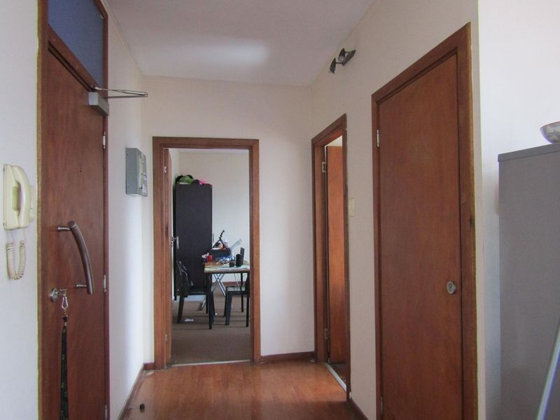 A functional apartment hallway featuring laminate flooring and multiple wooden door frames leading to adjacent rooms.
