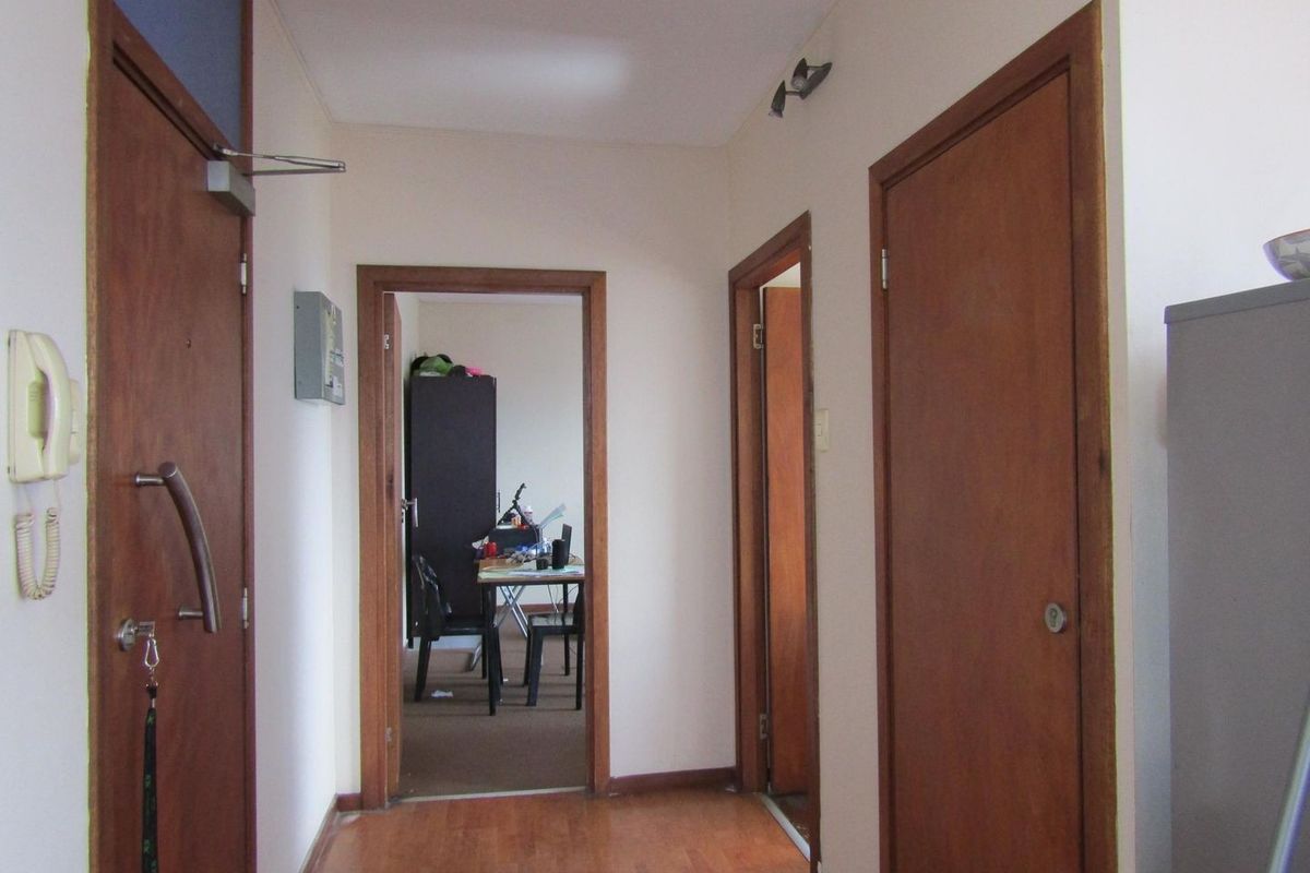 A functional apartment hallway featuring laminate flooring and multiple wooden door frames leading to adjacent rooms.