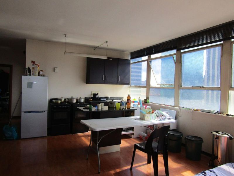 A functional kitchen area featuring dark cabinetry, a stove, and large windows that provide ample natural light, set against laminate flooring.