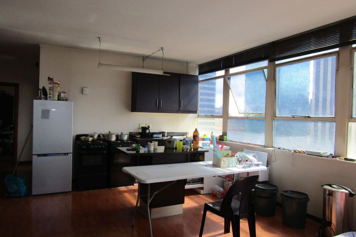 A functional kitchen area featuring dark cabinetry, a stove, and large windows that provide ample natural light, set against laminate flooring.