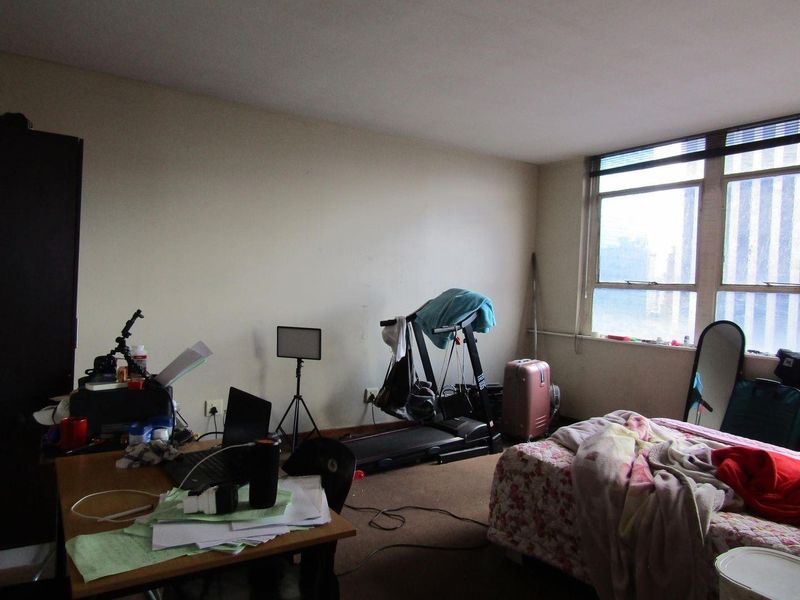 A bedroom featuring a large window providing natural light, with carpeted flooring and neutral wall finishes.