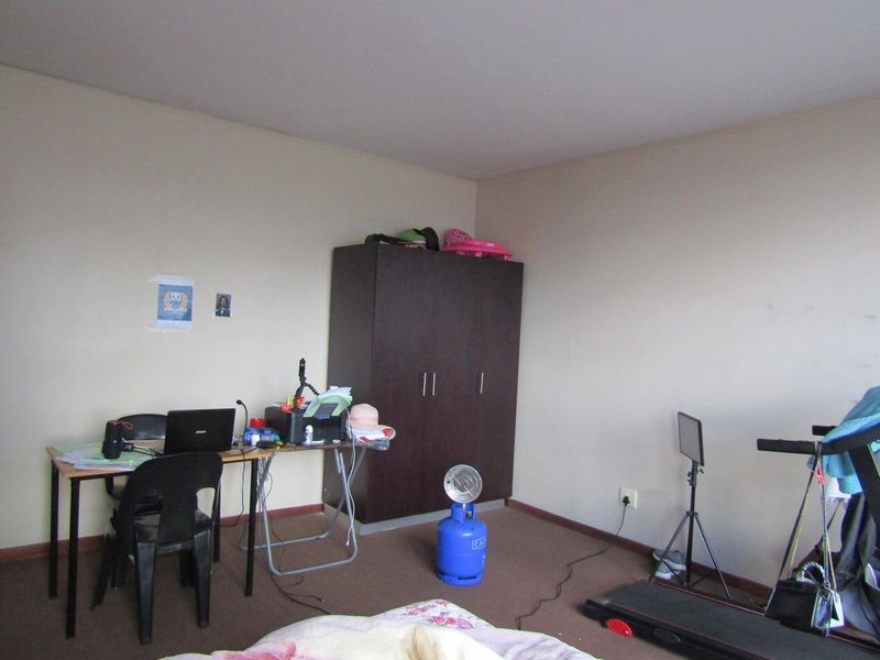 A bedroom featuring a built-in wardrobe and carpeted flooring, offering a functional space ready for personalization.