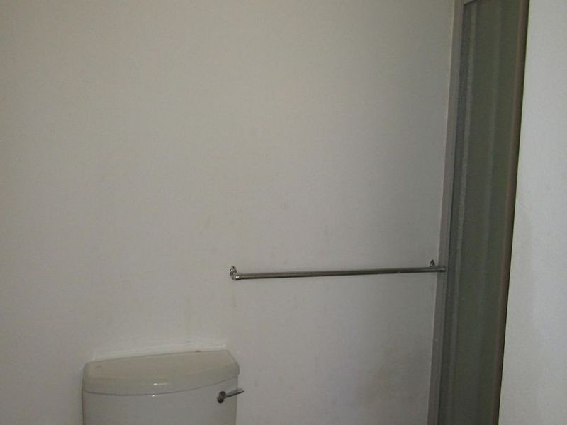 A compact bathroom featuring a standard toilet and a shower enclosure with a metal towel rail.