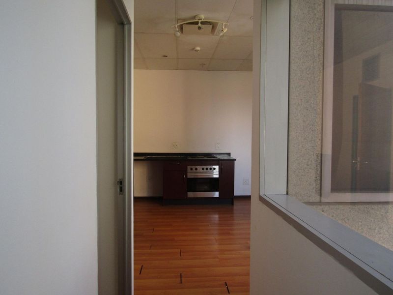 An empty kitchen area featuring laminate flooring, a built-in oven, and a hob, viewed through a doorway.