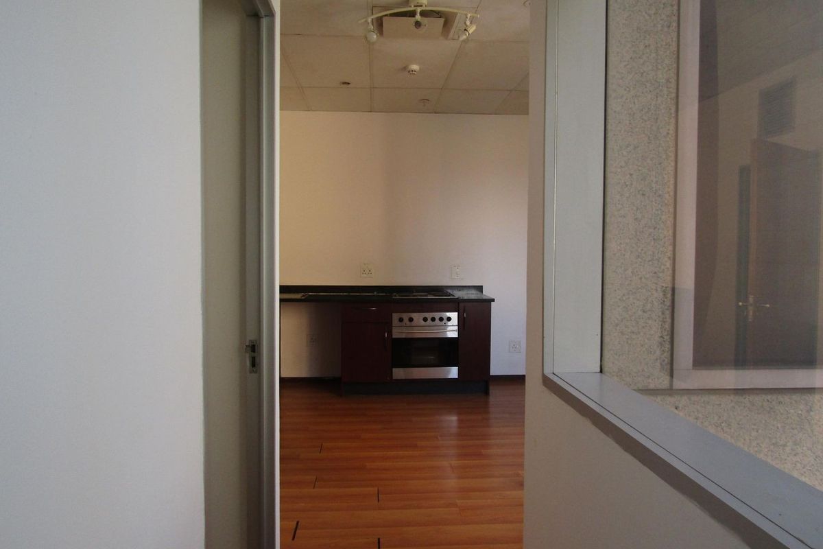 An empty kitchen area featuring laminate flooring, a built-in oven, and a hob, viewed through a doorway.