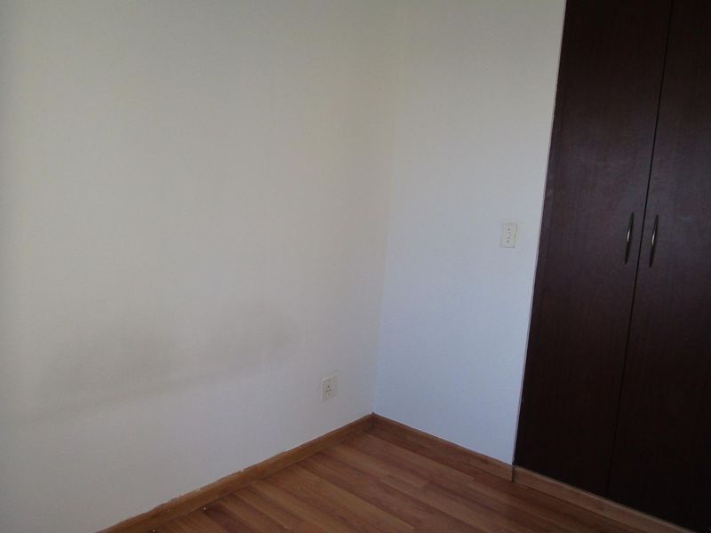 An empty bedroom featuring laminate flooring and a built-in dark wood wardrobe, requiring minor cosmetic wall repairs.