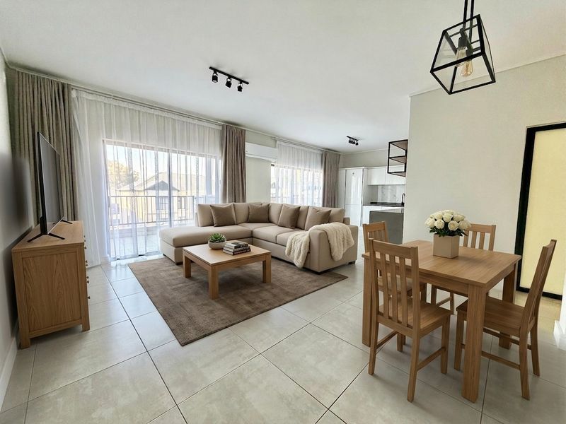 Spacious open-plan living and dining area featuring modern tiled floors, contemporary lighting, and seamless access to a private balcony.