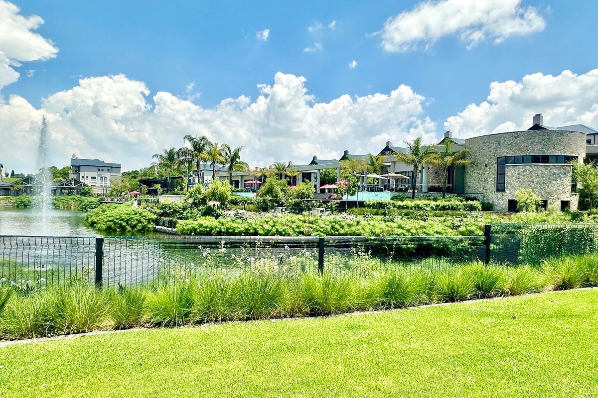 A scenic view of the rear exterior featuring a landscaped garden, a tranquil water feature, and stone-clad architectural elements of the penthouse complex.